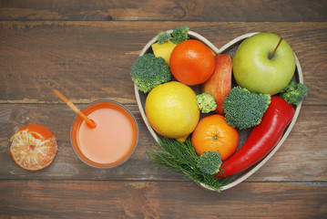 Fruits and Vegetables in Heart shaped Wooden Box. Broccoli, apples, Pepper, tangerine over Wooden Background. Banner. Health food Concept with copy space.
