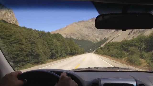 Driving Plate. Car on a Country Road, mountain range, valley - POV - Point of view front – windshield, dashboard, hands, steering wheel reference. Day.