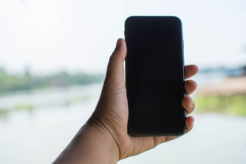 man touch screen smart phone and nature background. subject is blurred.