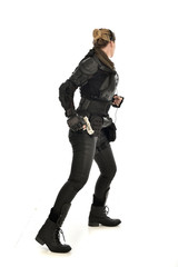full length portrait of female  soldier wearing black  tactical armour, holding a gun, isolated on white studio background.