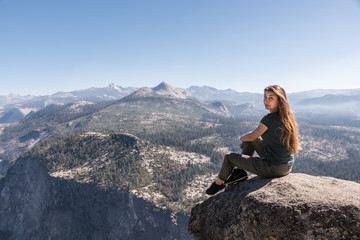 Fototapeta premium Girl is sitting on the Rock at Glacier Point in Yosemite National Park