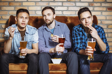 Young men with a beer watching the match on TV.