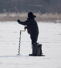 Fototapeta na wymiar A man catches fish on ice in winter