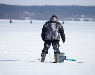 Fototapeta na wymiar A man catches fish on ice in winter