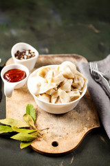 Traditional russian pelmeni, ravioli, dumplings with meat on concrete background. Russian food and russian kitchen concept. Selective focus