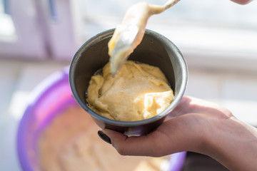 Woman puts the dough in a baking dish - natural light