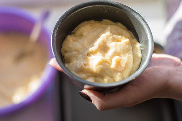 Woman puts the dough in a baking dish - natural light