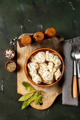 Traditional russian pelmeni, ravioli, dumplings with meat on concrete background.  Russian food and russian kitchen concept. Top view.