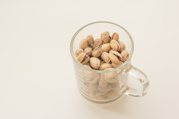 Glass mug and pistachio nuts on white background. Various nuts. Top view with copy space.