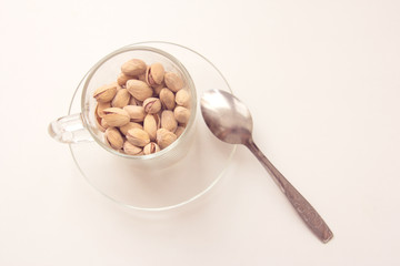 Glass cup and pistachio nuts on white background. Various nuts. Top view with copy space.