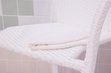 a white towel is on the chair. swimming pool.