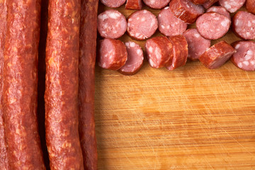 Thin smoked sausage whole and sliced on a wooden background. Close-up.