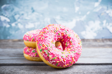 Donut with sprinkles on the rustic wooden background. Selective focus.