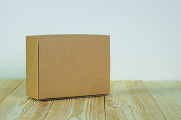 Empty closed brown cardboard box for mock up on the wooden table with copy space.