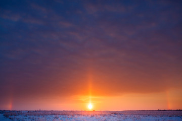 Sunrise over the meadow in the winter in a strong frost.