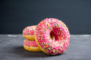 Donut with sprinkles on the rustic wooden background. Selective focus.