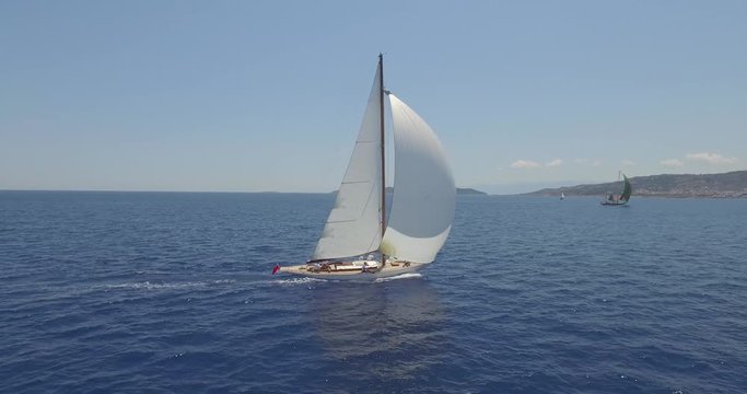 Aerial tracking shot of a traditional yacht sailing across Mediterranean seas