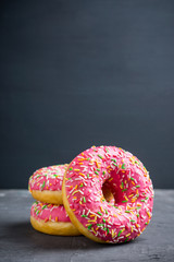 Donut with sprinkles on the rustic wooden background. Selective focus.