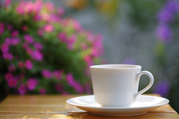Coffee in a white cup on wooden table at outdoor
