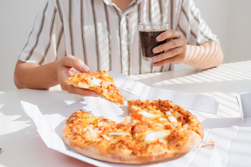 Cropped image of an asian man having lunch with pizza while working at his desk.