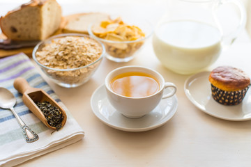 Useful rustic breakfast on the table - tea, oatmeal, milk and fresh cake - healthy eating concept