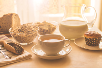 Useful rustic breakfast on the table - tea, oatmeal, milk and fresh cake - healthy eating concept