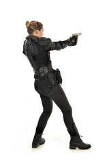 full length portrait of female  soldier wearing black  tactical armour, holding a gun, isolated on white studio background.