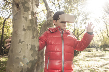 Little boy experiencing virtual reality with a DIY cardboard headset outdoors