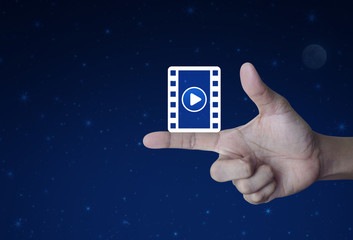 Play button with movie icon on finger over fantasy night sky and moon, Cinema online concept
