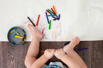 the child draws wax crayons on the floor