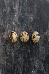 Three quail eggs on a black gray vintage background