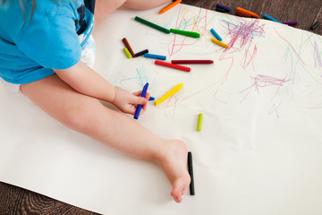 the child draws wax crayons on the floor