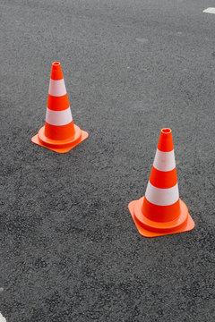 Deux cônes et signalisation sur du bitume neuf. Plots de trafic routier orange
