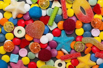 Multicolored candy and lollipops on a gray background.