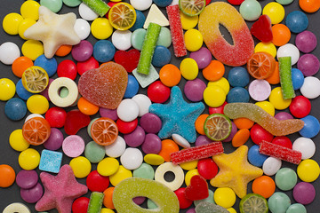 Multicolored candy and lollipops on a gray background.