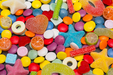 Multicolored candy and lollipops on a gray background.