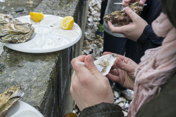 The man opens the oyster and clean plastic knife