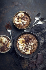 morning chocolate oat porridge with fresh bananas on black background - obrazy, fototapety, plakaty