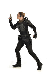 full length portrait of female  soldier wearing black  tactical armour, holding a gun, isolated on white studio background.