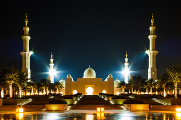 Beautiful night wide angle view of grandiose mosque with minarets and reflection on the pavement