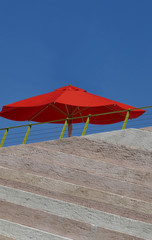 Wall of different colored granite and a red parasol