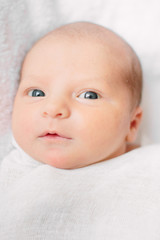 Cute newborn girl lying on furry cloth wearing white headband