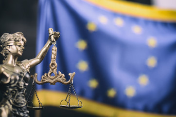 Scales of Justice, Justitia, Lady Justice in front of the European Union flag in the background.