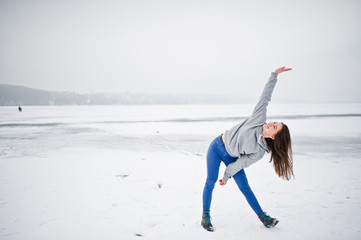 Funny girl wear on hoody sweater and jeans, at frozen lake in winter day.