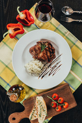 top view of plate with beef steak and glass of red wine on table napkin