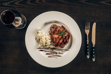 top view of plate with beef steak and glass of red wine on table