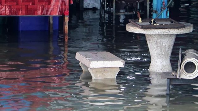Table with a bench on the flooded street, Samut Prakan. Water in the streets of the city, Thailand.
