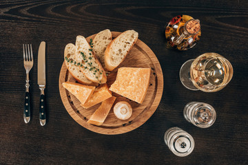 top view of parmesan cheese with baguette slices and mushroom on wooden board