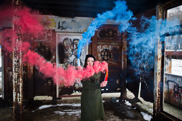 Young girl with blue and red colored smoke bomb in hands.