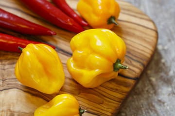 Close up of red and yellow hot peppers on cutting board on old wooden table
